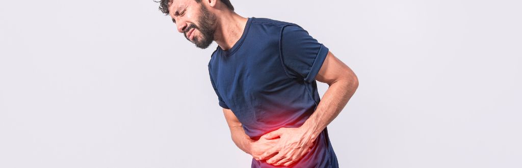man clasping stomach in pain